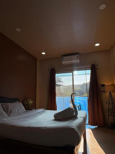 Un dormitorio con una cama grande con una ventana grande. en Art of greens, en Mahabaleshwar