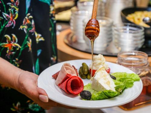 斯法克斯Ibis Sfax的一个人手里拿着一盘食物和一把勺子。