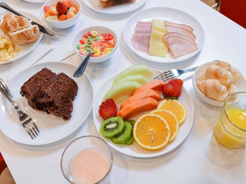 una mesa blanca cubierta con platos de comida y fruta en ibis budget Santos Gonzaga, en Santos