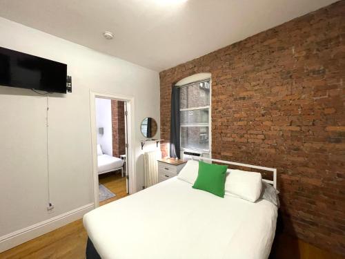 a bedroom with a white bed and a brick wall at Nest Aparthotel Broadway in New York