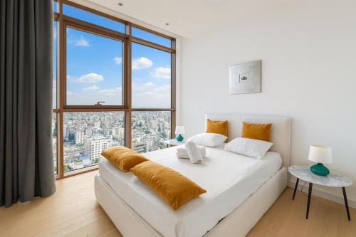 a bedroom with a white bed with a large window at SkyHigh Central 360 Gym & Pool in Nicosia