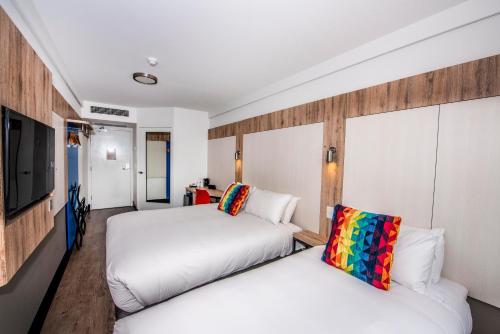 a hotel room with two beds and a flat screen tv at ibis budget Sydney Airport in Sydney