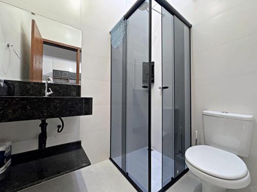 Un baño con inodoro y ducha de cristal. en Casa aconchegante piscina, en Matinhos