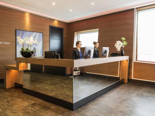 deux femmes debout à la réception dans l'établissement Adagio Paris 19ème Cité de la Musique, à Paris