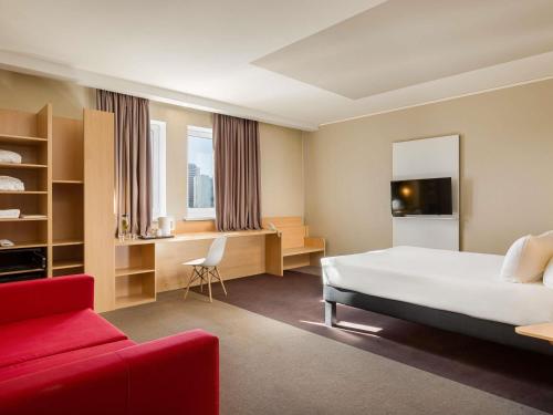 Una habitación de hotel con una cama y un sofá rojo. en ibis Kyiv Railway Station, en Kiev