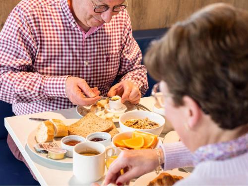 un hombre y una mujer sentados en una mesa desayunando en ibis budget Oostende Airport, en Ostende