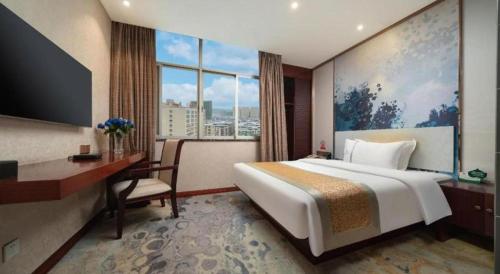a hotel room with a bed and a desk and a window at Nanning Qian Xi International Hotel in Nanning