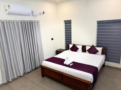 a bedroom with a large bed with purple pillows at Casa Linda Residency in Varkala