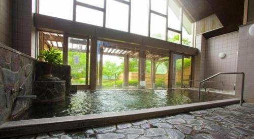 une grande chambre avec piscine d'eau dans un bâtiment dans l'établissement Takato Sakura Hotel, à Ina