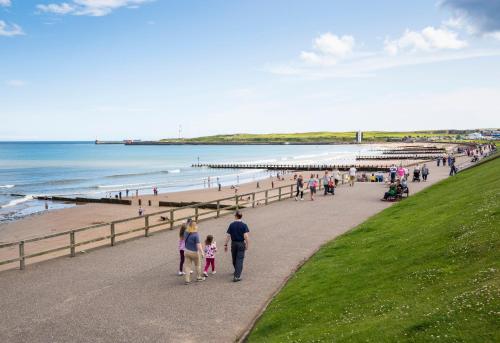 a group of people walking on a sidewalk near the beach at Aberdeen Lighthouse Cottages - coastal, dolphins in Aberdeen