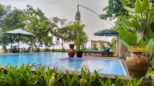 una piscina en un jardín con sombrillas en Rumah Arunika 27, 