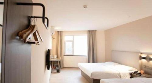 une chambre d'hôtel avec deux lits et une fenêtre dans l'établissement 7 Days Inn Tianjin Binhai Passenger Station Huabei Ceramics, à Binhai