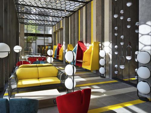 vestíbulo con sofá amarillo y sillas en ibis Styles Vung Tau, en Vung Tau