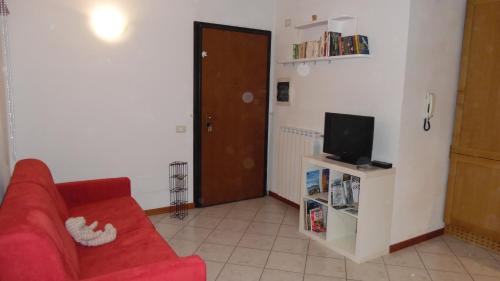 - un salon avec un canapé rouge et une télévision dans l'établissement Appartamento Luminoso, tra mare e lago, à Quiesa