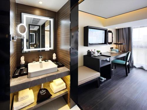 une salle de bain avec un lavabo et un bureau dans une chambre dans l'établissement Xana Hotelle Shenzheng South Station Foxconn, à Tiantangwei