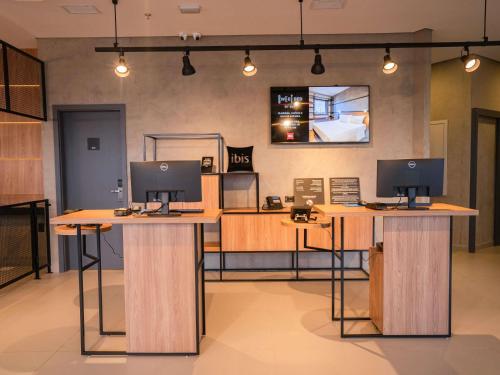 un bureau avec deux bureaux équipés d'ordinateurs dans l'établissement ibis Guarapuava, à Guarapuava