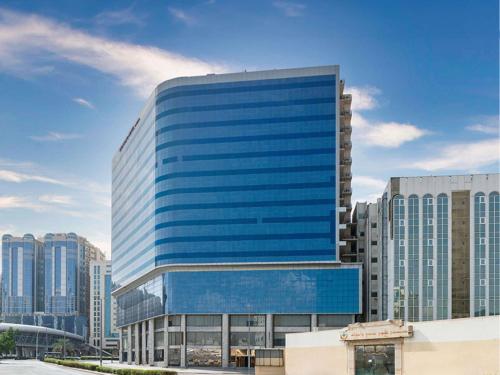 un edificio alto con ventanas azules en una ciudad en Mercure Makkah Aziziah, en La Meca