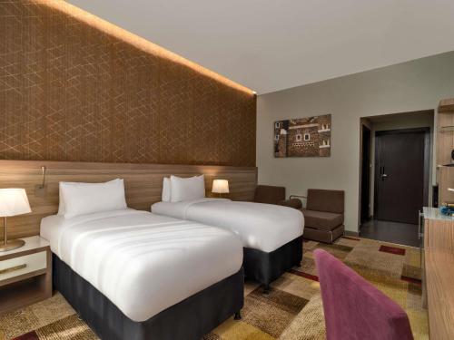 una habitación de hotel con dos camas y un sofá en Mercure Makkah Aziziah, en La Meca