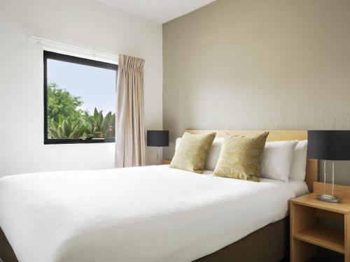 une chambre avec un grand lit blanc et une fenêtre dans l'établissement BreakFree Adelaide, à Adélaïde