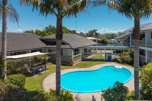 an aerial view of a house with a swimming pool and palm trees at Summit Motor Lodge in Tauranga