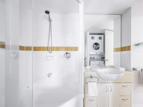 a white bathroom with a shower and a sink at BreakFree Alexandra Beach in Alexandra Headland