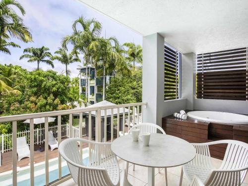 a balcony with a table and chairs and a bath tub at Mantra Aqueous on Port in Port Douglas