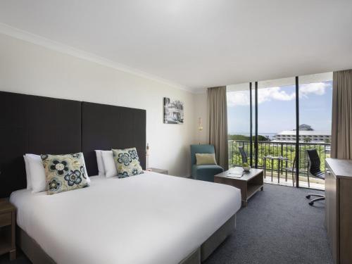 a hotel room with a large bed and a balcony at Mantra Esplanade in Cairns