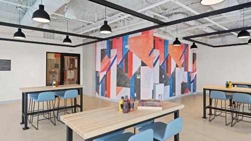 a room with tables and chairs and a large painting on the wall at Hyatus Luxury Residences Boston Everett Marquis Collection in Everett