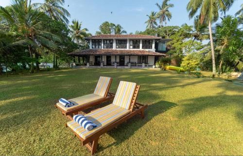 zwei Stühle auf einem Rasen vor einem Haus in der Unterkunft IslandOnBolgoda in Piliyandala