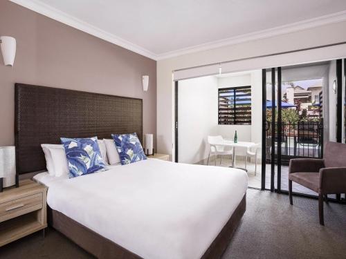 a bedroom with a large white bed and a chair at Mantra Heritage in Port Douglas