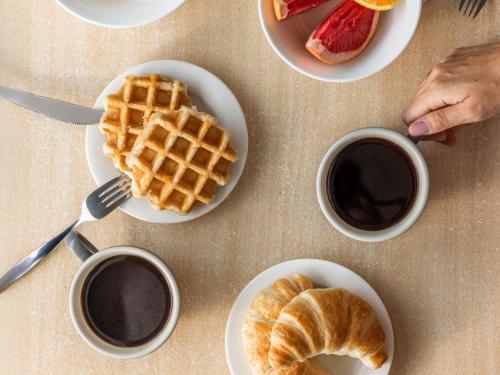 ポートダグラスにあるマントラ ポートシーのワッフルの皿とコーヒー2杯が置かれたテーブル