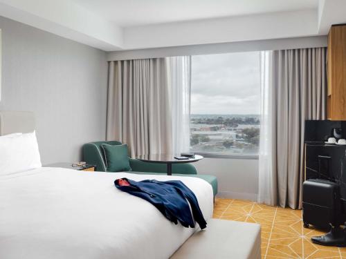a hotel room with a bed and a chair and a window at Mantra Melbourne Airport in Melbourne