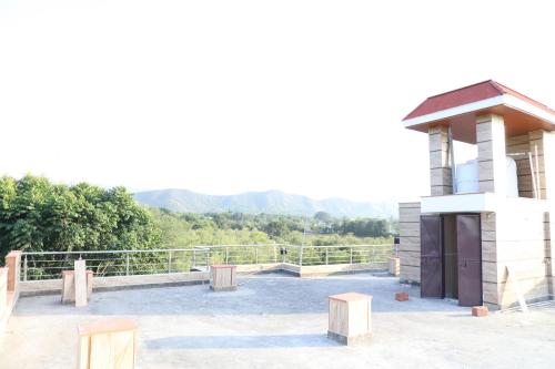 un pavillon avec un bâtiment et une montagne en arrière-plan dans l'établissement Eagle farmstay, à Pushkar