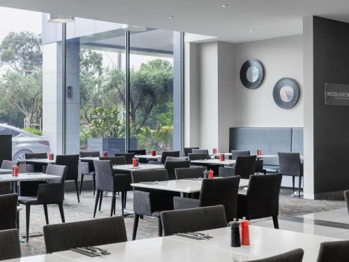 a dining room with tables and chairs and a clock on the wall at Mantra Melbourne Airport in Melbourne