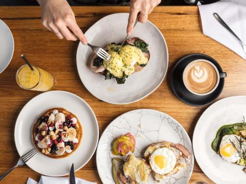 a table with plates of food and a person holding a fork at Peppers Silo Launceston in Launceston