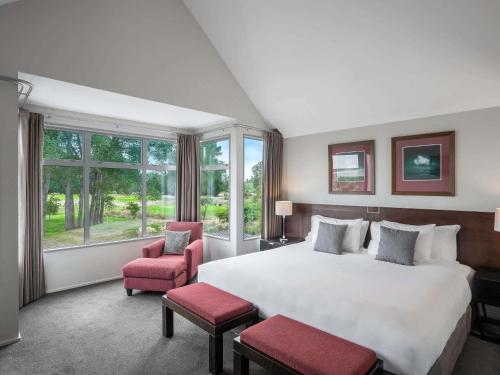 1 Schlafzimmer mit einem großen weißen Bett und 2 Stühlen in der Unterkunft Peppers Clearwater Resort in Christchurch