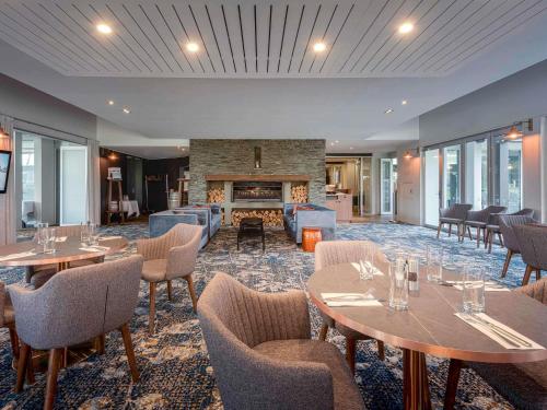 een restaurant met tafels en stoelen en een open haard bij Peppers Clearwater Resort in Christchurch