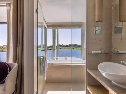 ein Badezimmer mit Waschbecken, Badewanne und Fenster in der Unterkunft Peppers Clearwater Resort in Christchurch