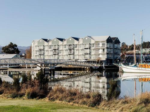 a large apartment building next to a river with a boat at Peppers Seaport Launceston in Launceston