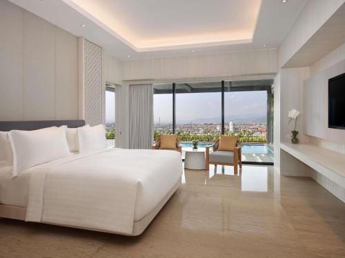 a bedroom with a white bed and a large window at Grand Mercure Lampung in Bandar Lampung