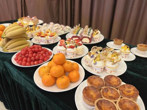 une table recouverte de assiettes de nourriture et de fruits dans l'établissement Vienna Hotel Guangxi Liuzhou Sanjiang Gulou Niaochao Passenger Station, à Sanjiang