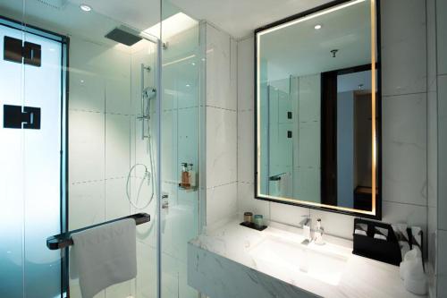 ein Badezimmer mit Dusche mit Spiegel und Waschbecken in der Unterkunft Borrman Hotel Baise High-speed Railway Station Hengning Plaza in Qitang