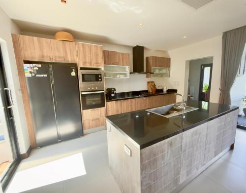a kitchen with a stainless steel refrigerator and cabinets at Phuket Hideaway Near Bang Tao in Laguna Phuket