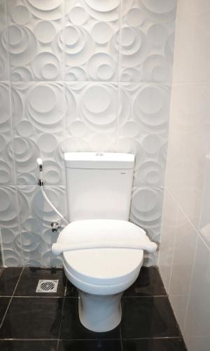 a white toilet in a bathroom with a wall at Luminor Hotel Pecenongan Jakarta By WH in Jakarta