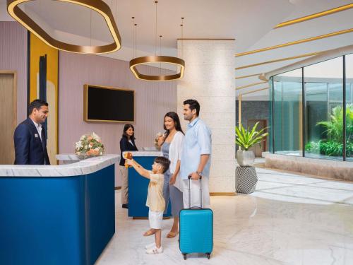 a family standing in a hotel lobby with a suitcase at Novotel Goa Panjim in Panaji