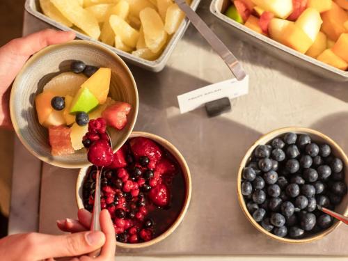 una persona que busca fruta en tazones sobre un mostrador en Novotel Goa Panjim, en Panaji