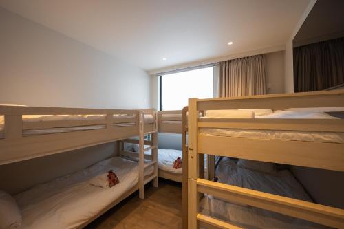 a room with three bunk beds and a window at Mokuren by H2 Life in Niseko