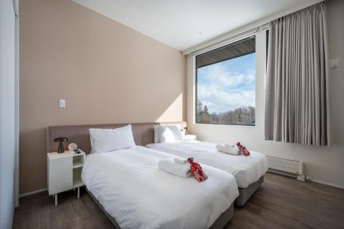 two beds in a room with a window at Mokuren by H2 Life in Niseko