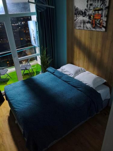 Un dormitorio con una cama con edredón azul y una ventana. en Двухкомнатная кватира с видом на горы, en Batumi