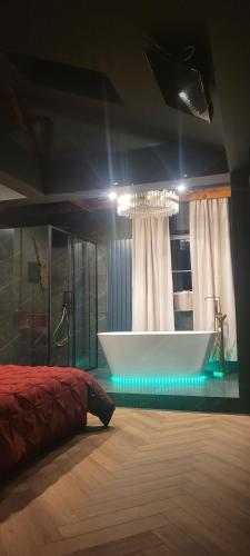 a bedroom with a bath tub and a chandelier at Apartament Plac Zabaw in Łódź